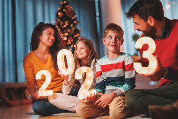 Family holding illuminative numbers 2023 while celebrating New Year