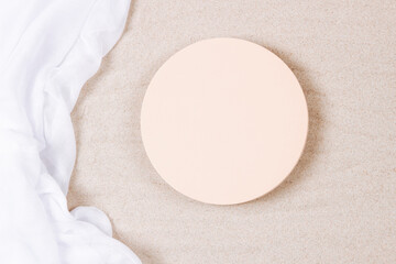 Empty round beige platform podium and white crumpled linen fabric cloth on white natural beach sand...
