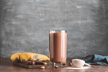 Chocolate milkshake smoothie with banana, protein powder and nuts on dark background