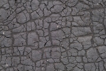 Weathered old dark gray ruberoid texture with numerous cracks and fractures, sun-scorched surface for use as a background.
