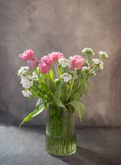 Vase with beautiful pink tulips and dianthus in green vase.