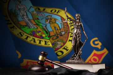 Idaho US state flag with statue of lady justice, constitution and judge hammer on black drapery....