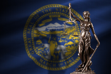 Nebraska US state flag with statue of lady justice and judicial scales in dark room. Concept of...