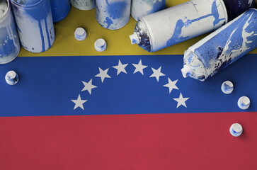 Venezuela flag and few used aerosol spray cans for graffiti painting. Street art culture concept,...