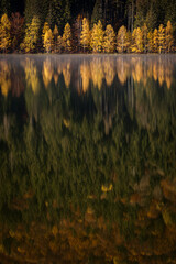 Beautiful colourful landscape in autumn season with rays of light in forest and lake reflection. Romania