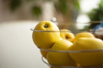Group of yellow apples in the plate on the table at home.