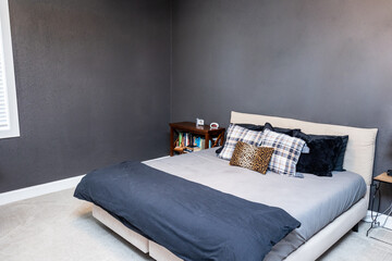 A large teenage boys bedroom with navy blue walls and a queen king bed