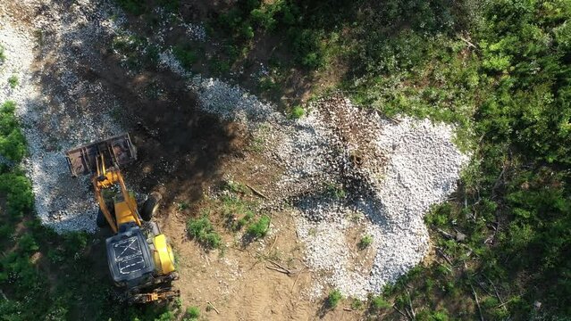 A modern tractor on a construction site from the air. A yellow wheel loader lifts and moves garbage. Heavy machinery is working at the facility.