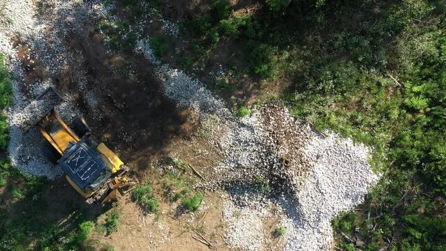 A modern tractor on a construction site from the air. A yellow wheel loader lifts and moves garbage. Heavy machinery is working at the facility.