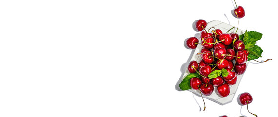 Ripe sweet cherries with fresh mint leaves isolated on white background. Trendy beton stand