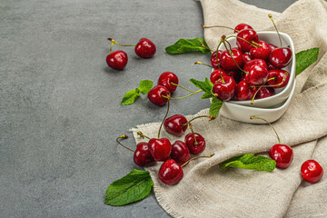 Ripe sweet cherries with fresh mint leaves, traditional summer fruits. Trendy stands, vintage napkin
