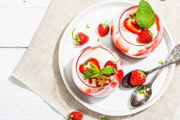 Italian dessert panna cotta in glass with strawberries. Healthy sweet food, hard light, dark shadow