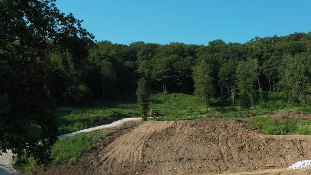A modern tractor on a construction site from the air. A yellow wheel loader lifts and moves garbage. Heavy machinery is working at the facility.