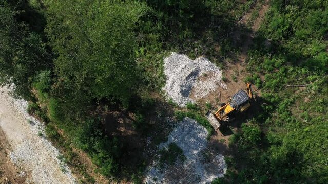 A modern tractor on a construction site from the air. A yellow wheel loader lifts and moves garbage. Heavy machinery is working at the facility.