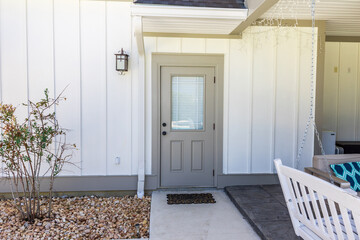 A taupe rear side back door of a new construction cream color house with hardy board siding near...