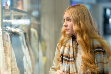 Fototapeta na wymiar Shopping. A young girl looks at shop window.