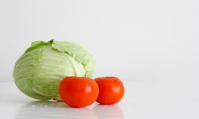 Fresh vegetable cabbage and tomatos natural food on a white table.