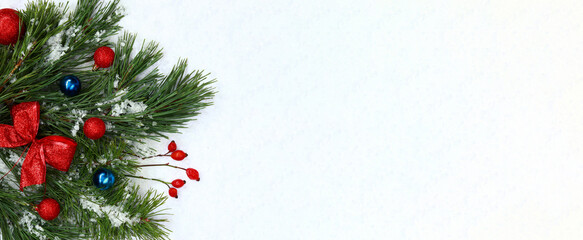Bouquet of fir branches and Christmas balls with a red bow. Christmas composition on snow, background with empty space