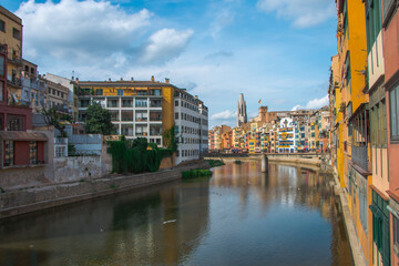 Colorful yellow and orange houses and famous house Casa Maso reflected in water river Onyar, in Girona, Catalonia, Spain. Church of Sant Feliu and Saint Mary Cathedral at background.