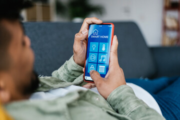 Internet of things. Young hispanic latin man using smart home app on mobile phone. IOT concept