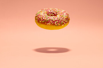 Levitating pink donut on pink background. Creative food background. Minimal wallpaper