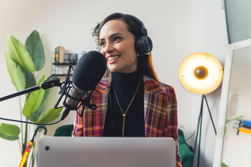 Young cheerful brunette woman recording a podcast at home studio. High quality photo