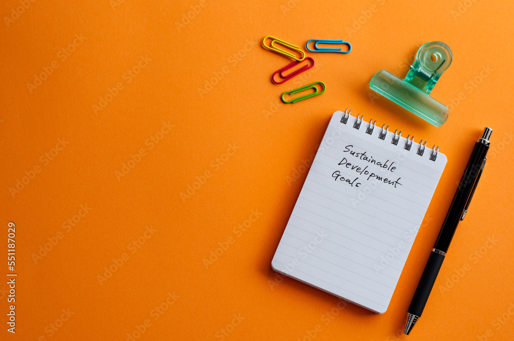 Aufkleber there is a notebook with the word sustainable development goals. it's placed on a color background.