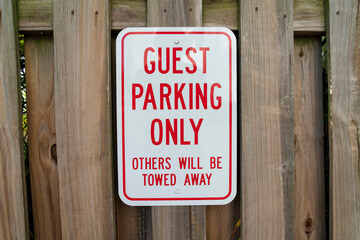 Sign on a wooden fence with Guest Parking Only Others Will Be Towed Away- Miami, Florida