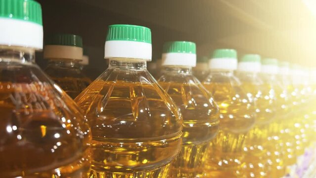 Sunflower or corn oil in plastic bottles is on the shelf in a supermarket or a warehouse. Closeup shot