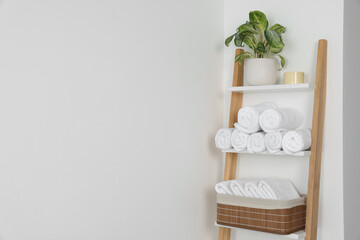 Fototapeta na wymiar Soft towels on decorative ladder near white wall, space for text