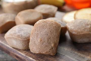 Frozen banana puree cubes on wooden board, closeup