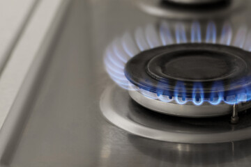 Gas burner with burning flame on cooktop, closeup