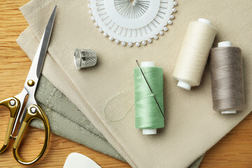 Flat lay composition with threads and sewing tools on wooden table