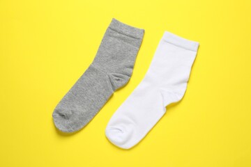 White and grey socks on yellow background, flat lay