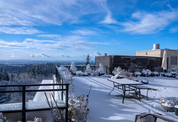 Snowed-in BC rooftop patio with spectacular winter view across valley to clouds on horizon.
