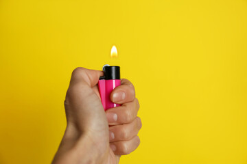 Woman holding pink lighter on yellow background, closeup. Space for text - obrazy, fototapety, plakaty