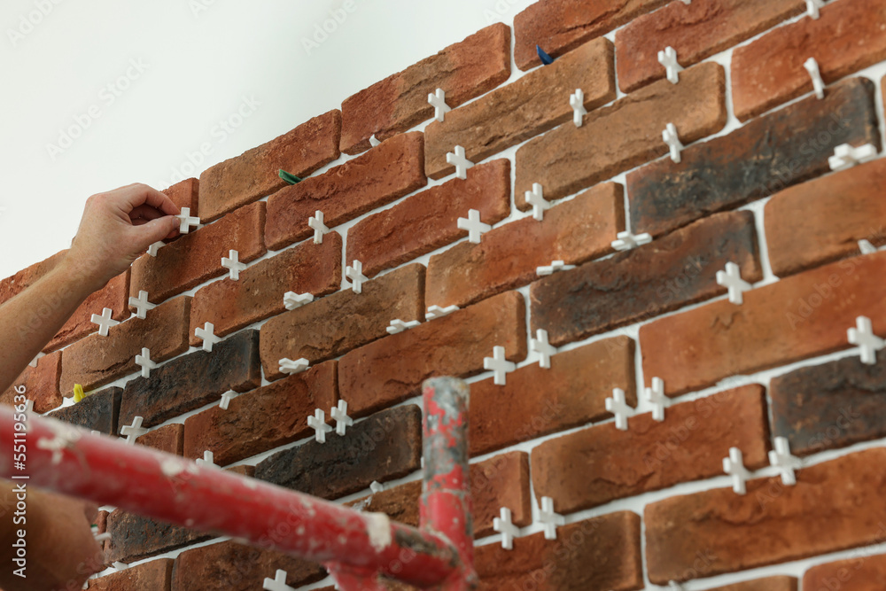 Sticker Professional builder gluing decorative brick on wall, closeup. Tiles installation process