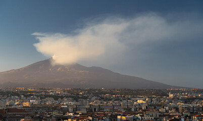 Port of Catania. Volcano Etna with white smoke and blue sky on background. Sicily, Italy