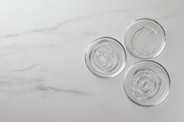 Petri dishes with liquids on white marble table, flat lay. Space for text