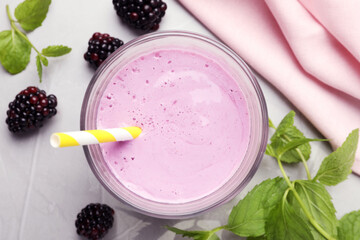 Delicious blackberry smoothie in glass and berries on white table, flat lay