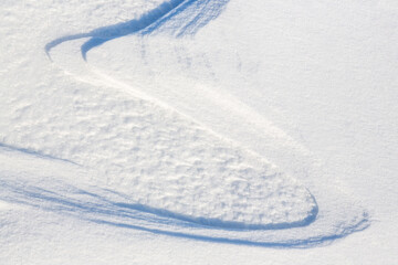 Beautiful winter background with snowy ground. Natural snow texture. Wind sculpted patterns on snow surface.
