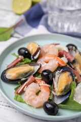 Plate of delicious salad with seafood on white wooden table, closeup