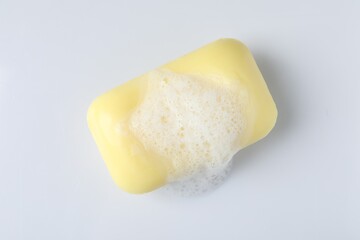 Soap with fluffy foam on white background, top view