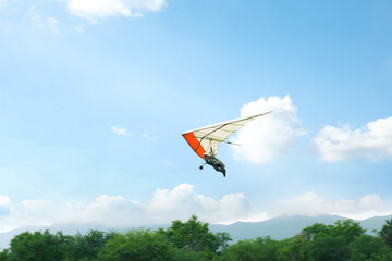 Person on hang glider flying in sky, space for text