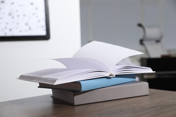 Stack of different hardcover books on wooden table indoors
