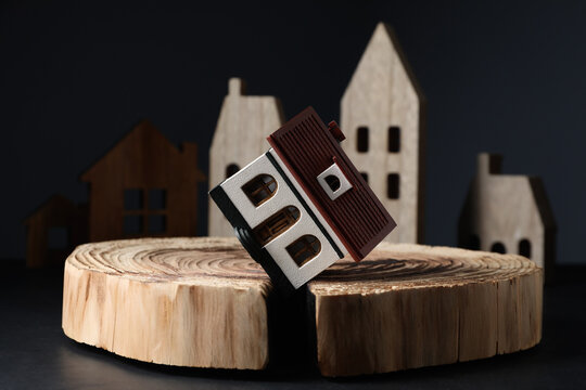 House model in cracked wooden stump on black table depicting earthquake disaster
