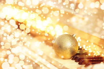 Beautiful golden bauble and fairy lights on piano. Christmas music. Bokeh effect