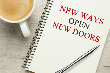 Phrase New Ways Open New Doors and cup of coffee on white wooden table, flat lay