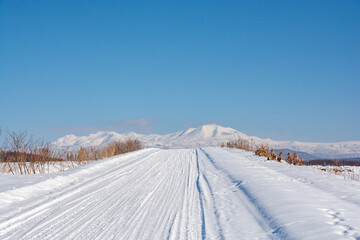 Fototapeta na wymiar 冬の晴れた日の雪道と雪山　大雪山 