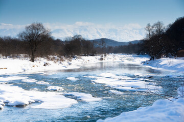 冬の河原と雪山と青空　十勝岳連峰

